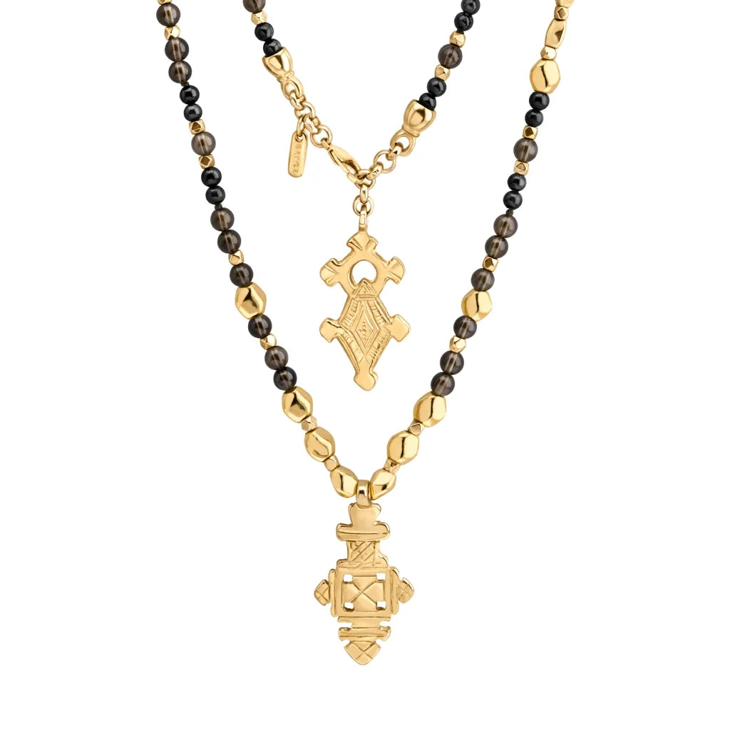 Collar de 112cm en baño de oro 22K, con una composición de piedras de 6mm y cuentas doradas, complementando un dije de cruz africana barroca - Joyería y bisutería fina