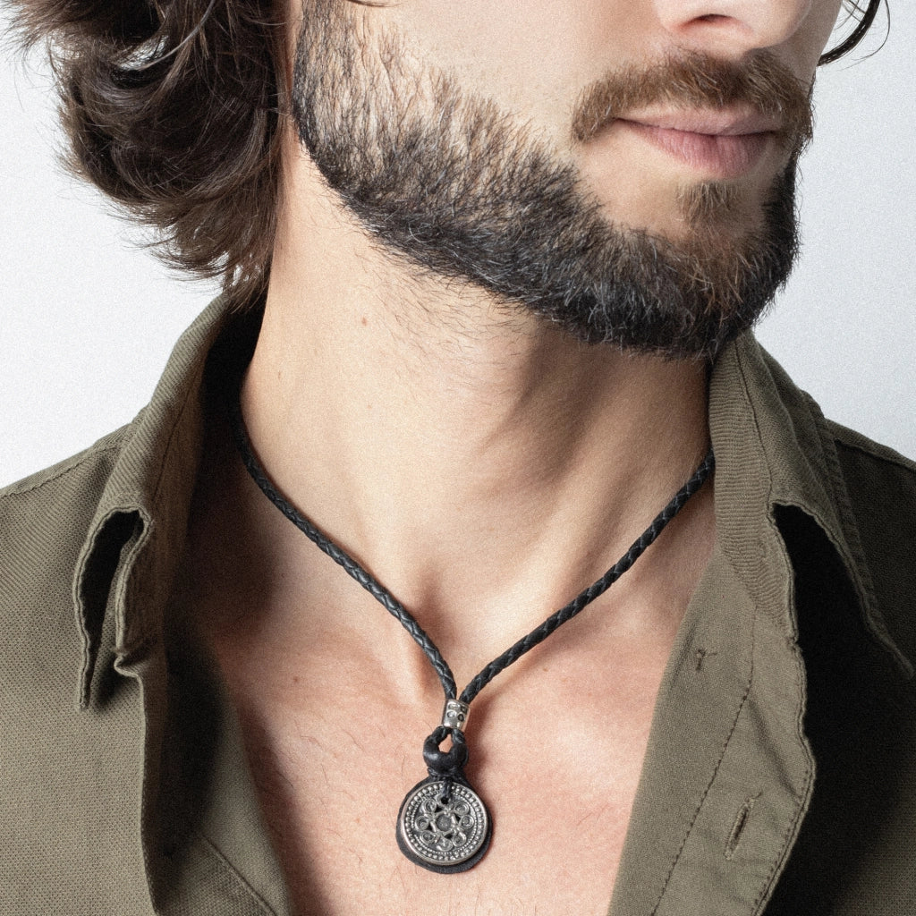 Collar para hombre de piel trenzada con dije de moneda tibetana en acero pulido. Corso Joyería - Joyería y bisutería fina